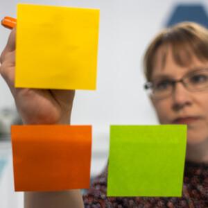 Nainen toteuttamassa palvelumuotoilua värikkäillä post-it-lapuilla.