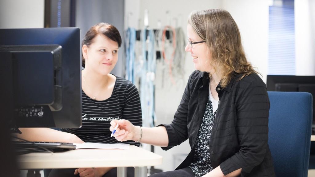 Johtajuuden tikkaat -hanke keskittyy maatalouden johtamiskulttuurin kehittämiseen. Kaksi naista keskustelee johtamisasioista pöydän ääressä tietokoneen ruudun edessä.