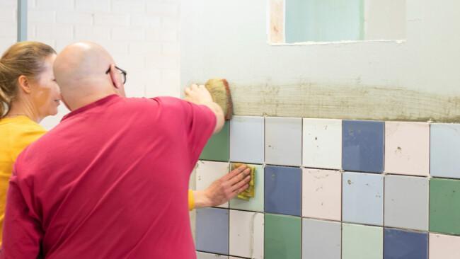 Sisustaja-remontoijat laatoittavat seinää.