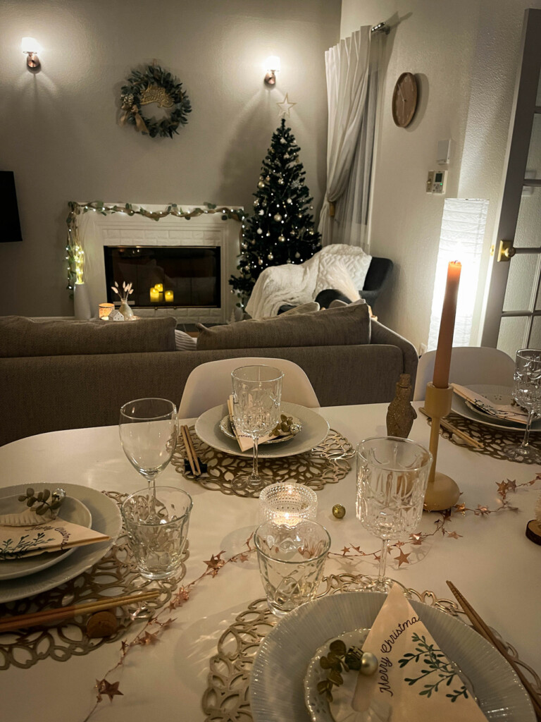 Näkymä jouluisesta juhlapöydästä olohuoneen suuntaan, jossa näkyy joulukuusi ja seinällä kranssi. Kyseessä on Hanna Hämäläisen tekemä joulustailaus japanilaiseen kotiin.