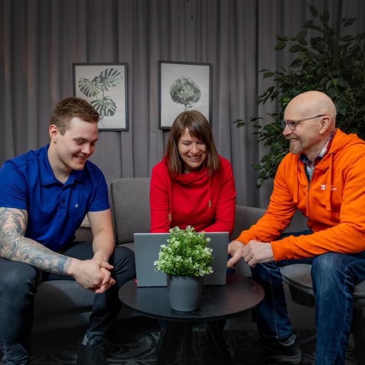 Kolme henkilöä istuu sohvalla läppärin edessä ja katsoo Suomen Yrittäjäopiston maatalouden koulutusmahdollisuuksia.