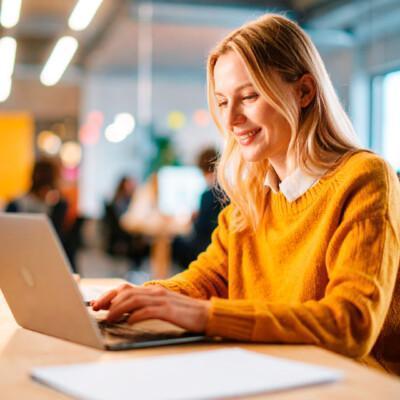 Nainen osallistumassa läppäriltään Suomen Yrittäjäopiston webinaarisarjaan. Tekoälykuva.