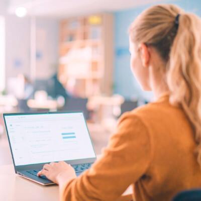 Nainen osallistumassa Suomen Yrittäjäopiston asiantuntijawebinaariin omalta läppäriltään. Tekoälykuva.