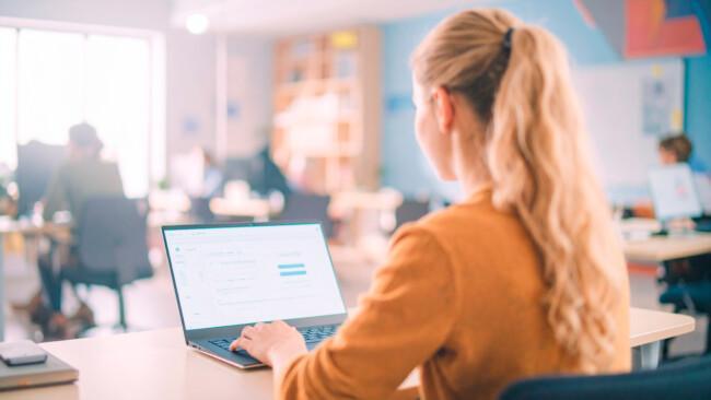 Nainen osallistumassa Suomen Yrittäjäopiston asiantuntijawebinaariin omalta läppäriltään. Tekoälykuva.