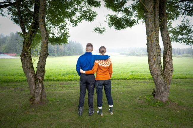 Nuori viljelijäpariskunta katsoo peltomaisemaa.