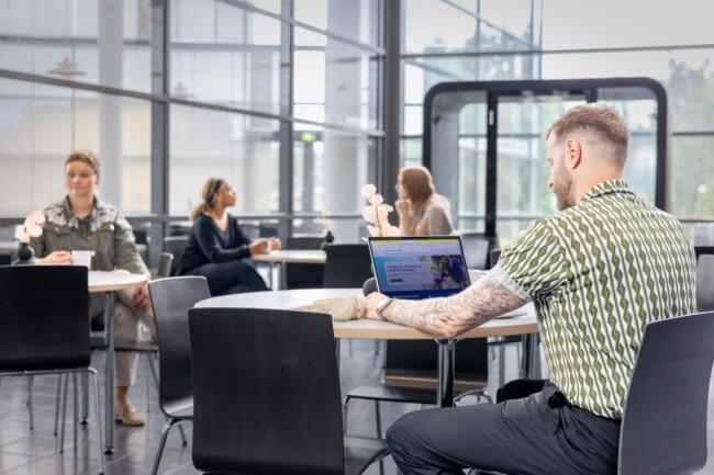 Mies istuu pöydän ääressä ja selaa Mikroyrityksen Digiloikka -hankkeen sivustoa kannettavalta tietokoneelta.
