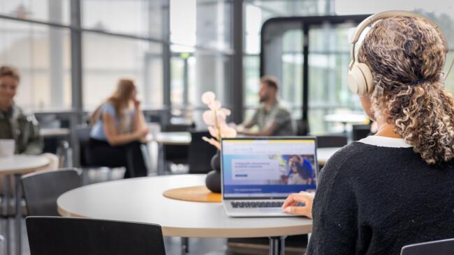 A person studying on an online Entrepreneurship degree training in a coffee shop.