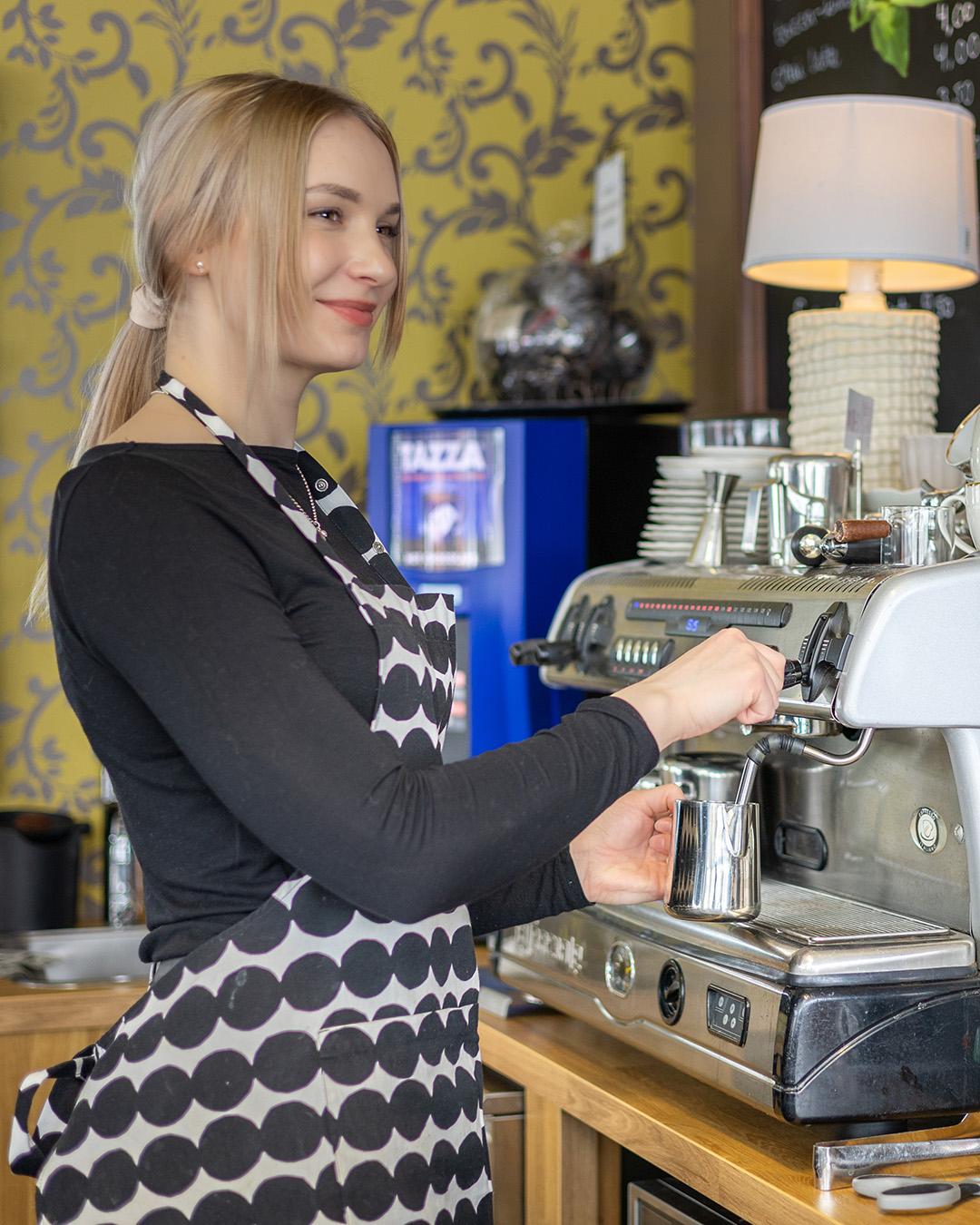 Barista kahvikoneen äärellä tekemässä kahvia.