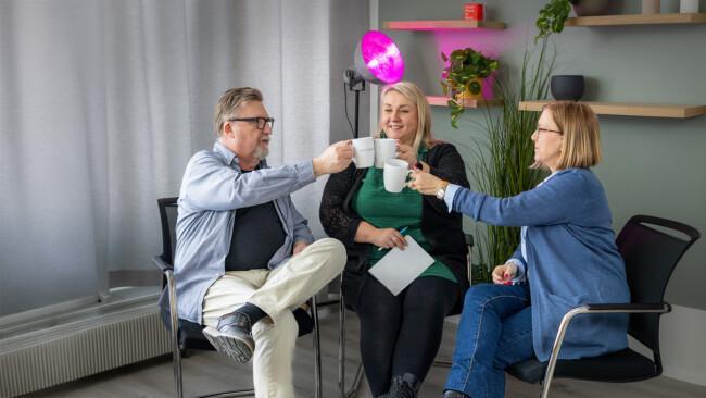 Kolme henkilöä kippistämässä kahvikupeilla onnistuneen rekrytoinnin päätteeksi.